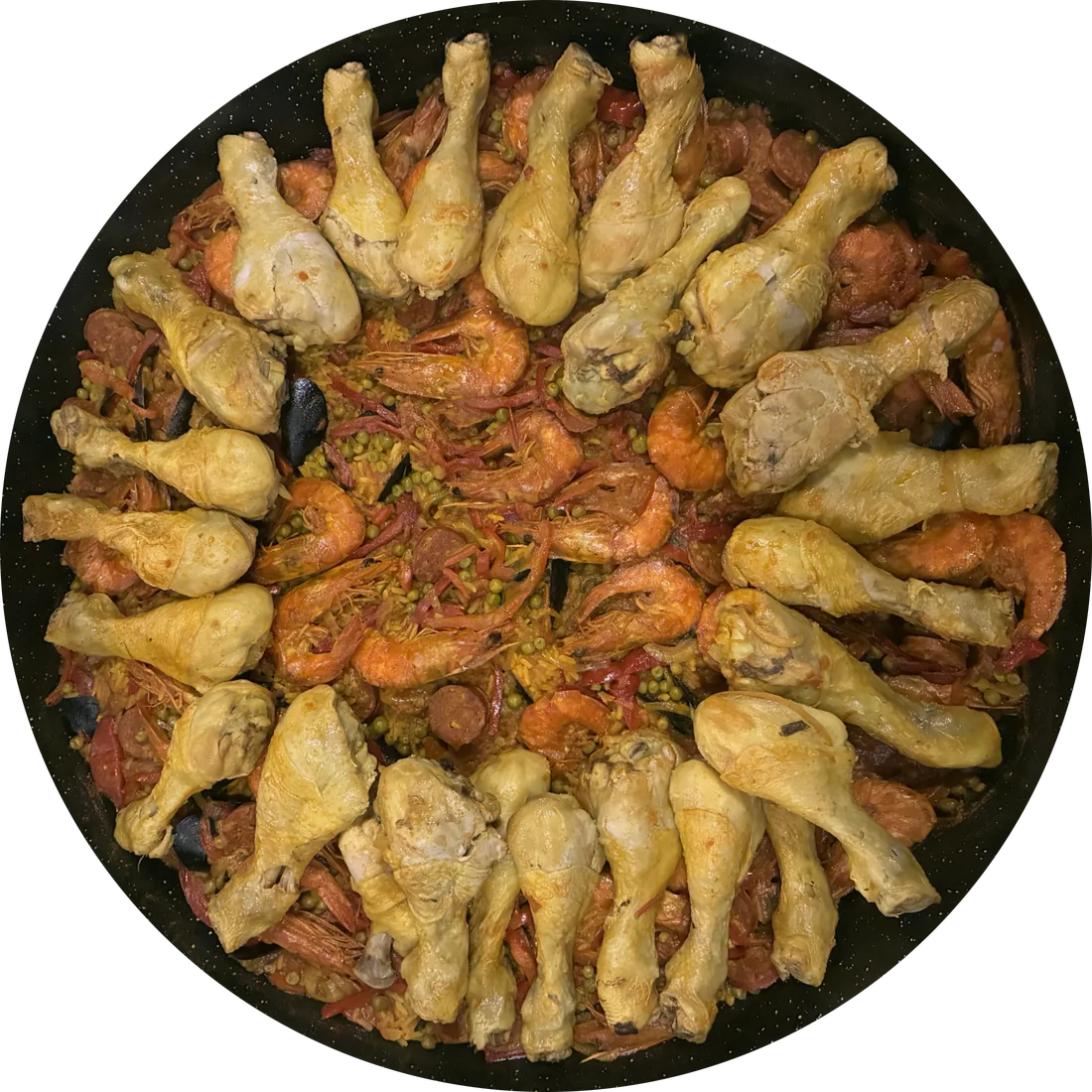 La paëlla du chef vue du dessus dans la grande poêle : poulet, gambas, moules, chorizo et petits pois